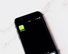 Fehér asztalon fekvő okostelefon, amelyen a WhatsApp alkalmazás látható