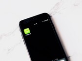 Fehér asztalon fekvő okostelefon, amelyen a WhatsApp alkalmazás látható