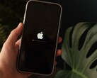 Egy kéz tart egy iPhone-t, a képernyőn az Apple logó és egy haladási sáv világít.