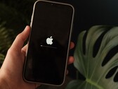 Egy kéz tart egy iPhone-t, a képernyőn az Apple logó és egy haladási sáv világít.
