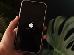 Egy kéz tart egy iPhone-t, a képernyőn az Apple logó és egy haladási sáv világít.
