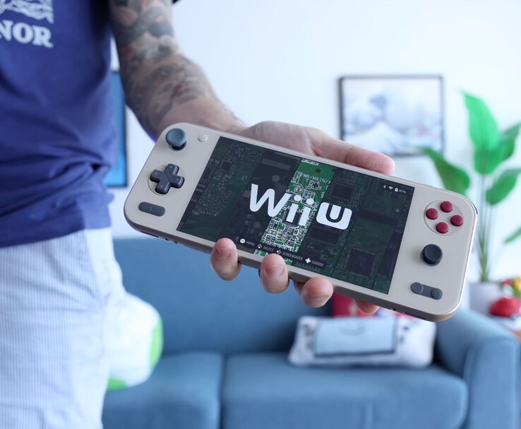 Russ a Retro Game Corps-tól, kezében az Ayaneo Pocket S2 kézikonzollal, amelyen egy Wii U emulátor fut, és a készülék egy nappaliban látható. (Kép forrása: Retro Game Corps)