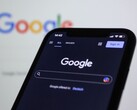Okostelefon, amely a Google keresőoldalát jeleníti meg egy Google-logóval ellátott képernyő előtt