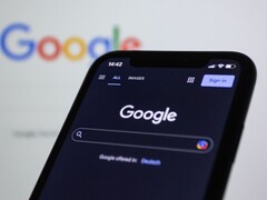 Okostelefon, amely a Google keresőoldalát jeleníti meg egy Google-logóval ellátott képernyő előtt