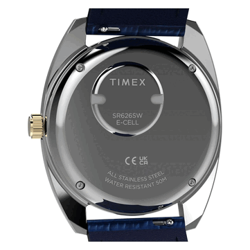 Az aranyszínű Timex Q 1976 Day and Date hátulnézete, amelyen a rozsdamentes acél hátlap, az elemtartó rekesz és az 50 méteres vízállóságot jelző felirat látható.