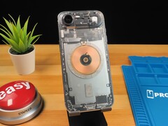 Átlátszó iPhone Air, amely a belső alkatrészeket és a réz töltőtekercset mutatja egy fa asztalon. (Kép forrása: Phone Repair Guru via YouTube)