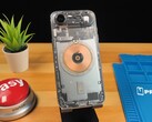 Átlátszó iPhone Air, amely a belső alkatrészeket és a réz töltőtekercset mutatja egy fa asztalon. (Kép forrása: Phone Repair Guru via YouTube)