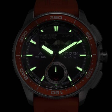A Citizen Promaster Wave Tracker JV3000-13E gyenge fényviszonyok között készült felvételen a Citizen Promaster Wave Tracker JV3000-13E izzó mutatói és órajelzői sötét háttér előtt.
