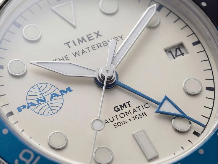 A Timex Pan Am Waterbury Automatic GMT karóra közeli képe, amelyen látható az ezüstfehér számlap, a világító órajelölők, a dátumablak és a Pan Am márkajelzés.