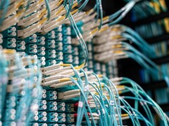 Kék száloptikai kábelek fehér csatlakozókkal, amelyek egy adatközpont patch paneljébe vannak dugva