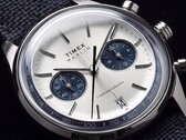 Közeli kép a Timex Marlin Jet Chronograph TW2Y89900 óráról, amelyen látható az ezüstfehér számlap, a sötétkék segédszámlapok, a rátett óraindexek, a pálcamutatók, a tachiméterskála és a dátumablak.