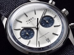 Közeli kép a Timex Marlin Jet Chronograph TW2Y89900 óráról, amelyen látható az ezüstfehér számlap, a sötétkék segédszámlapok, a rátett óraindexek, a pálcamutatók, a tachiméterskála és a dátumablak.