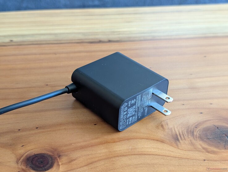 A Lenovo Yoga Slim 7 14 készülékhez mellékelt 65 W-os USB-C hálózati adapter. Figyeljük meg a visszahúzhatatlan hálózati csatlakozókat és a másik végén található beépített USB-C kábelt.