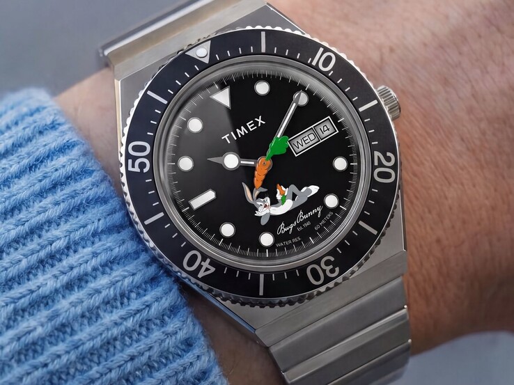 A csuklón viselt Timex Looney Tunes x M79 Automatic fekete számlapján Bugs Bunny látható, répa alakú másodpercmutatóval, nap- és dátumkijelzéssel, valamint fekete, forgatható lünettával.