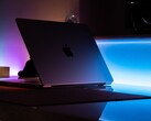 Félnyitott MacBook egy sötét szobában, a résből fény szűrődik az asztalra