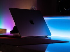 Félnyitott MacBook egy sötét szobában, a résből fény szűrődik az asztalra