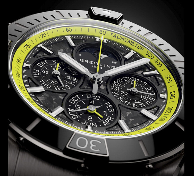 Közeli felvétel a Breitling Super Chronomat B19 44 Perpetual Calendar Chronograph karóráról, amelyen jól látható a szénszálas számlap, a naptár segédszámlapjai, az ezüstszínű mutatók és a lime-zöld tachiméterskála.