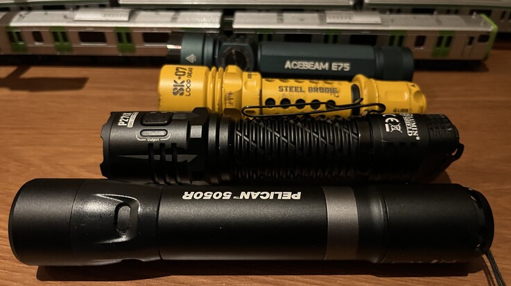 A Loop Gear sárga SK-07-es modellje az Acebeam E75-tel (hátul), a Nitecore P27i-vel és a Pelican 5050R-rel összehasonlítva