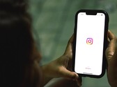 Egy nő, aki mindkét kezében egy okostelefont tart, a kijelzőn az Instagram kezdőképernyője látható