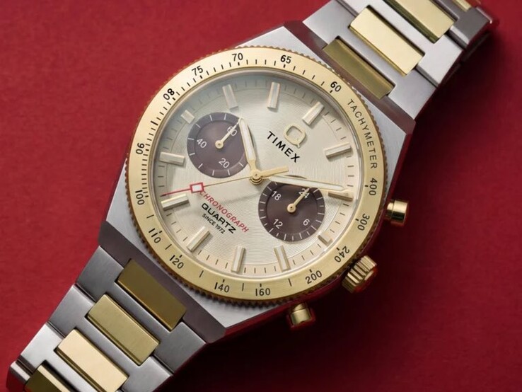 Közelkép a csuklón viselt Timex Q Timex Continental Chronograph TW2Y92300 óráról, amelyen látható az arany színű számlap, a barna kis számlapok, a tachyméter keret és a két színű rozsdamentes acél karkötő.