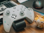 Fehér Xbox kontroller egy fa asztalon egy kis macskafigura mellett (Kép forrása: FOX ^.ᆽ.^= ∫ via Pexels)